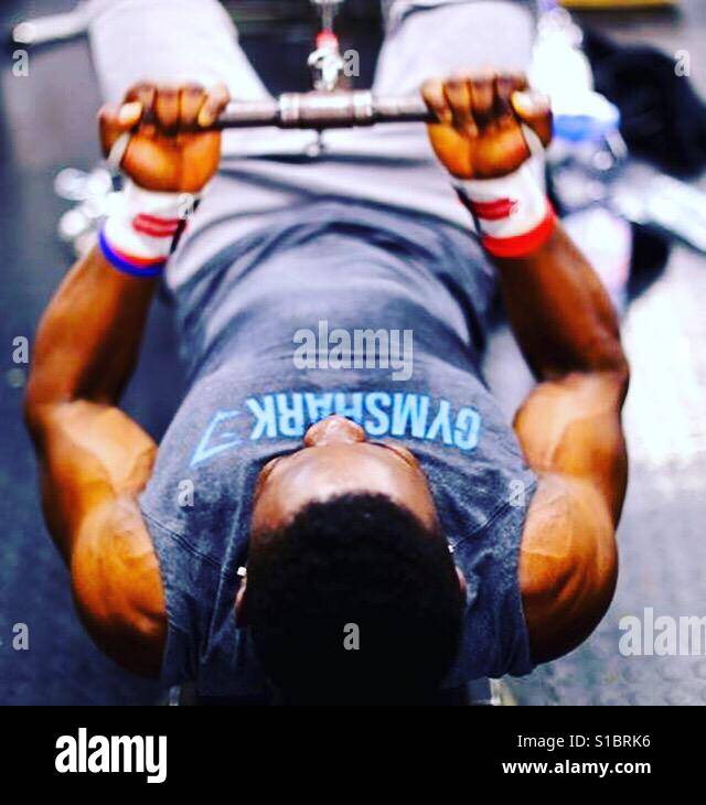 Schwarzen muskulöser Mann auf seinem Rücken ziehen Gewichte Stockfoto