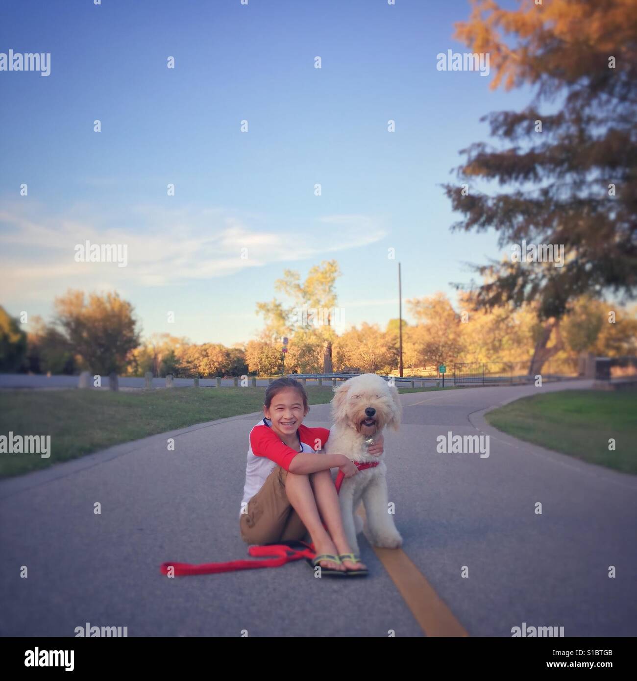 Mädchen und Hund sitzen auf einen jogging-Pfad. Stockfoto
