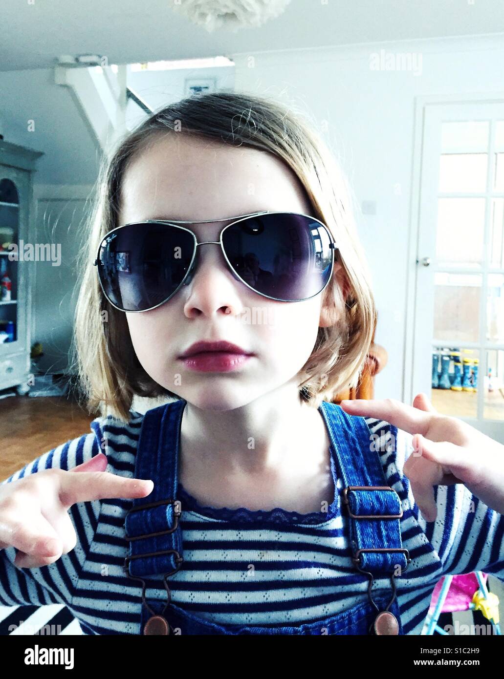 Mädchen mit Sonnenbrille auf drinnen - Smartphone-aufgenommenes Stockfoto