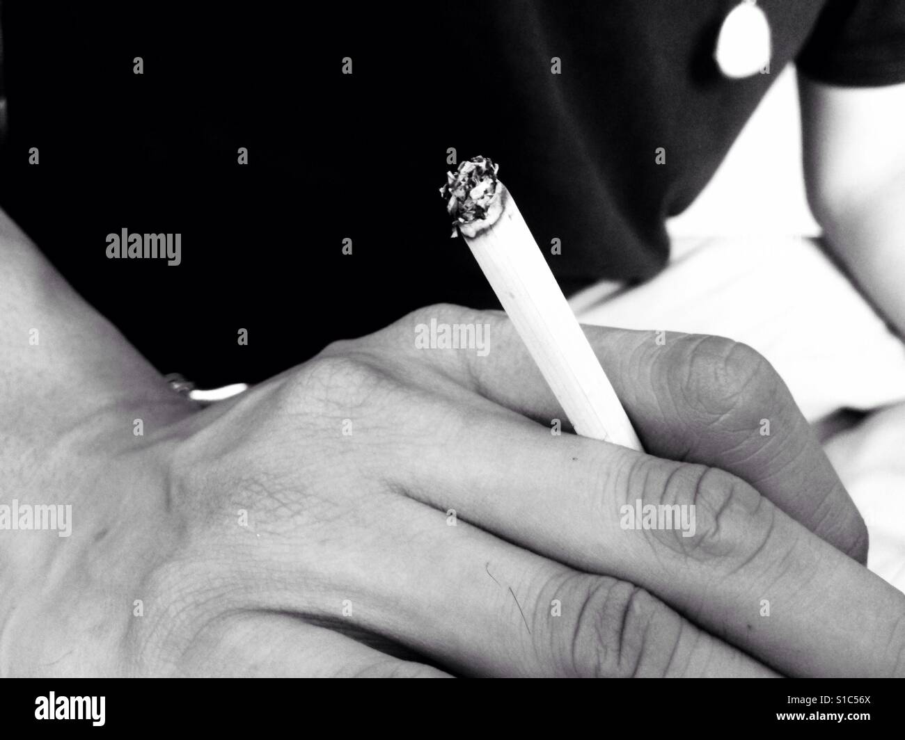Ein Mann mit Zigarette mit zwei Finger - Hand und Zigarette - schwarz und weiß Stockfoto