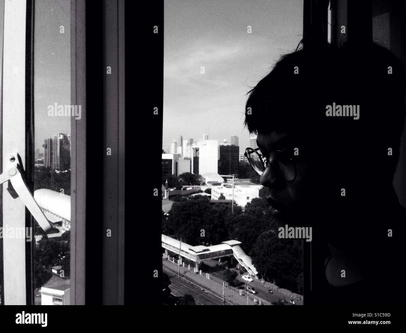 Asiatischer Mann schaut aus dem Fenster - schwarz / weiß Stockfoto