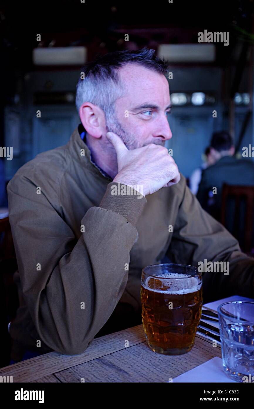 Mann sitzt in der Kneipe Bier trinken Stockfoto
