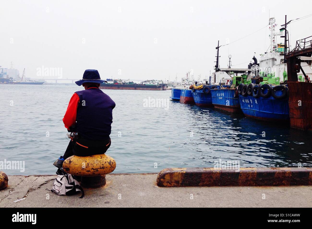 Fischer, die sitzen in der Nähe von Hafen mit vielen Booten und Schiffen Stockfoto