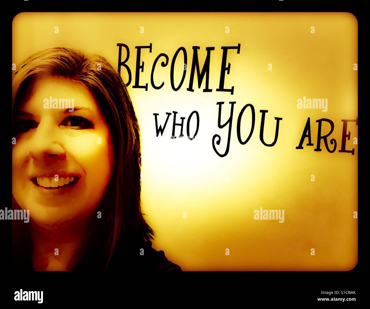 Frau entspannt und lächelnd mit sign'Become, wer du bist "hinter ihr. Stockfoto