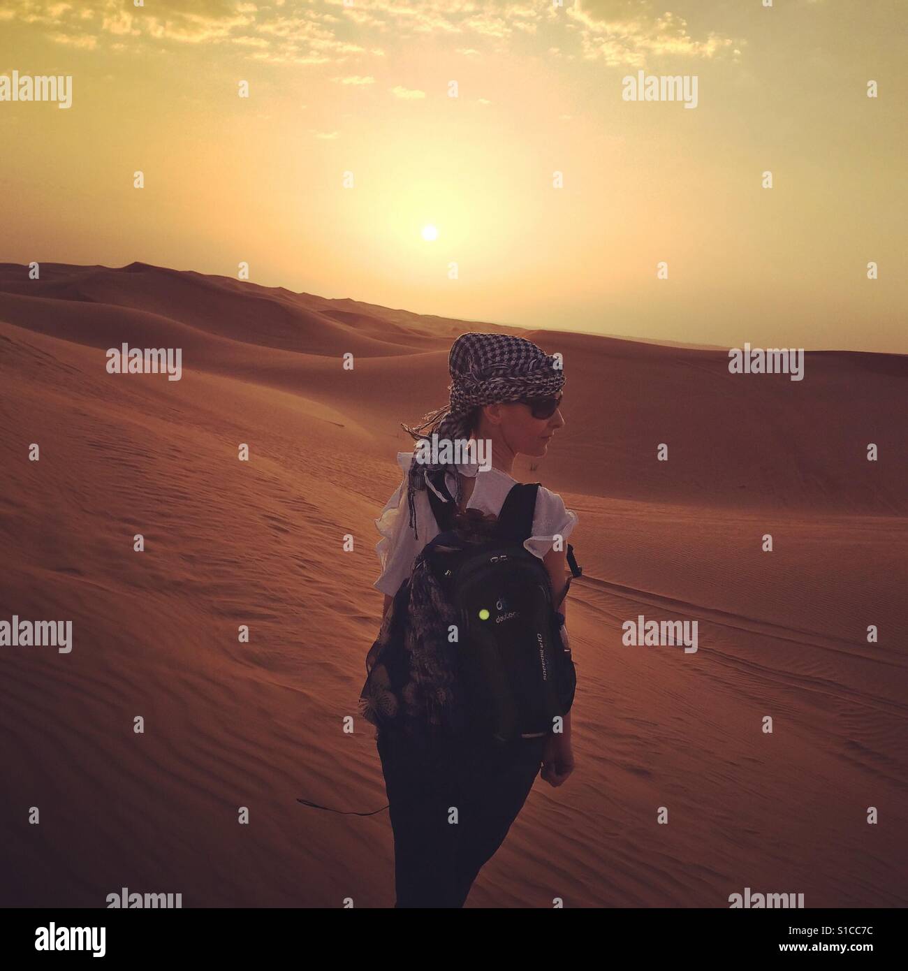 Eine Frau mit einem Rucksack auf, in der Wüste, Dubai, Vereinigte Arabische Emirate - Smartphone-aufgenommenes Stockfoto