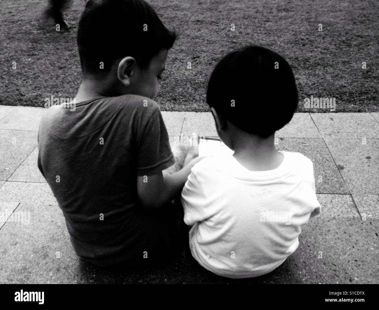 Zwei Kinder spielen Gadget auf dem Park - schwarz / weiß Stockfoto