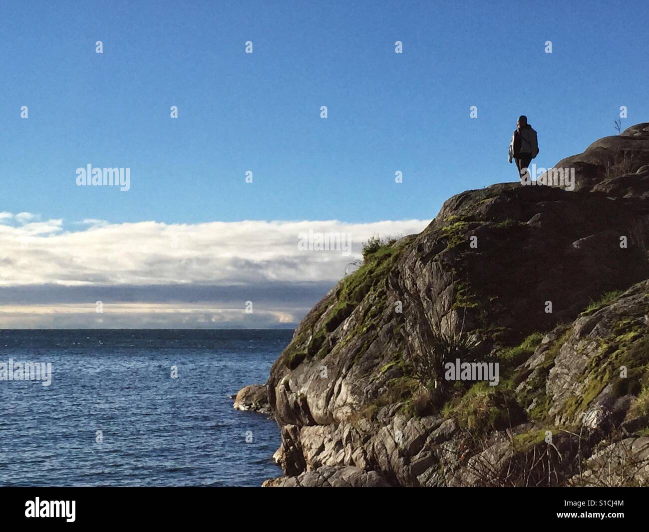 Einsame Person am Rand auf einer Klippe direkt am Meer, Blick auf die Meereslandschaft. Stockfoto
