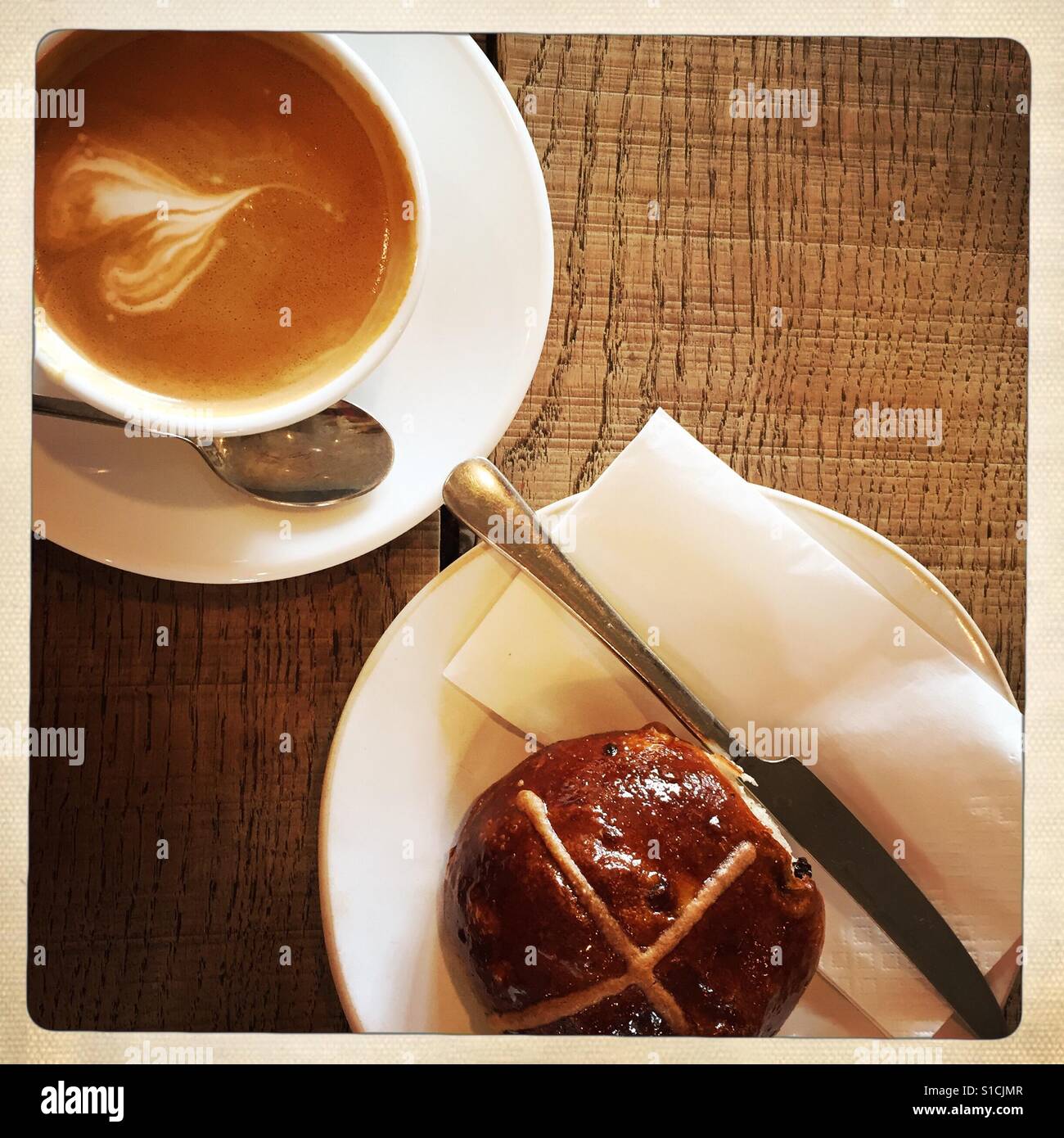 Kaffee und Hot Cross Bun auf einem Tisch Stockfoto