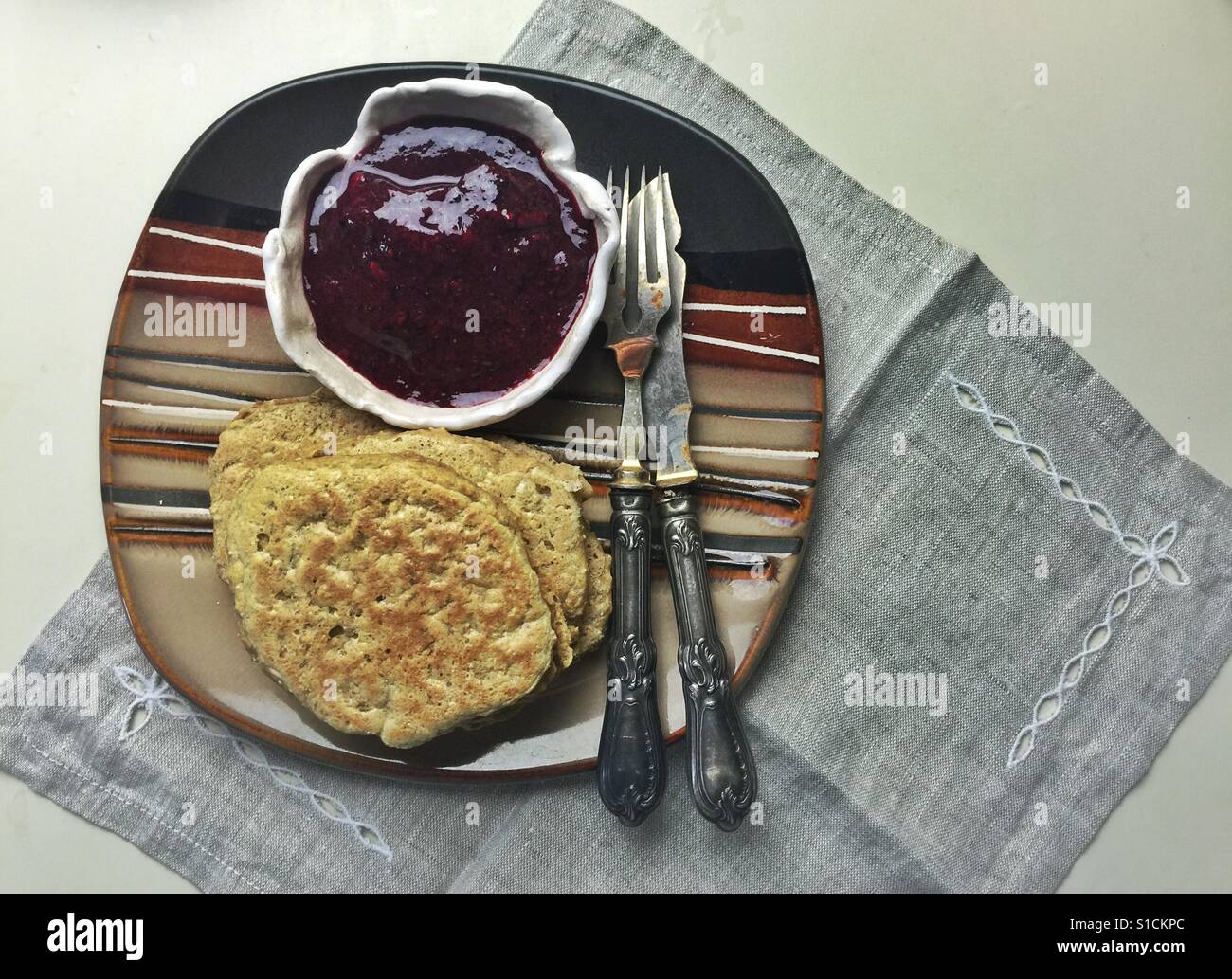 Vegane Haferflocken Pfannkuchen mit Marmelade auf. moderne Platte mit Vintage itensils Stockfoto