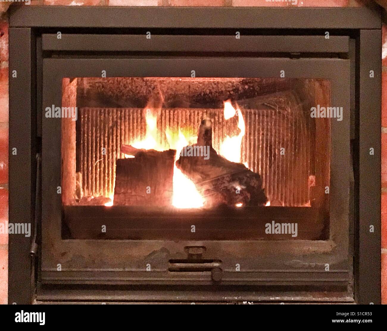 Feuer in einem hölzernen brennenden Ofen mit einem Stück Holz, das aussieht wie eine Kaninchen-Silhouette. Stockfoto