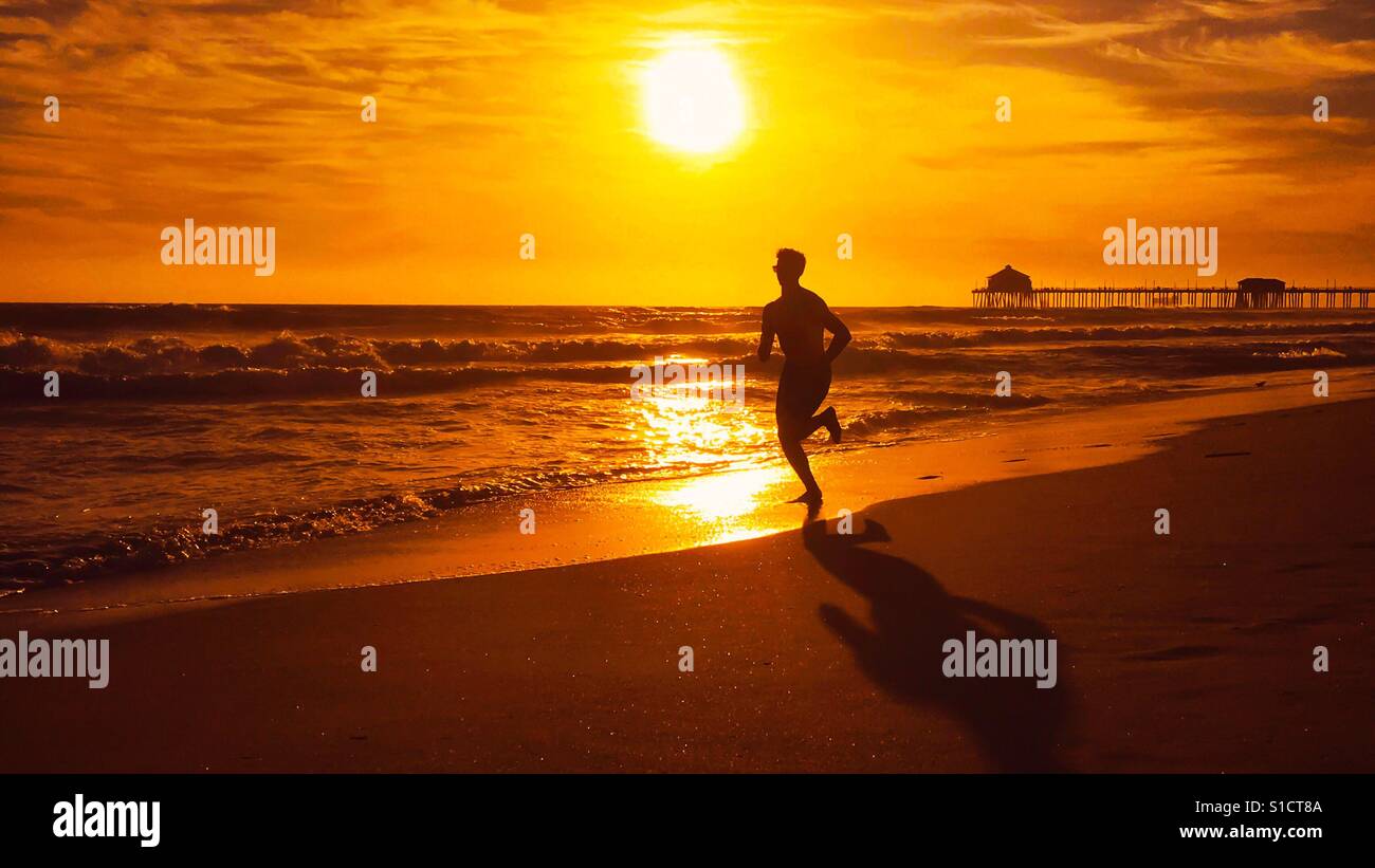 Junger Mann läuft auf eine California Beach bei Sonnenuntergang. Platz für Kopie. - Smartphone-aufgenommenes Stockfoto