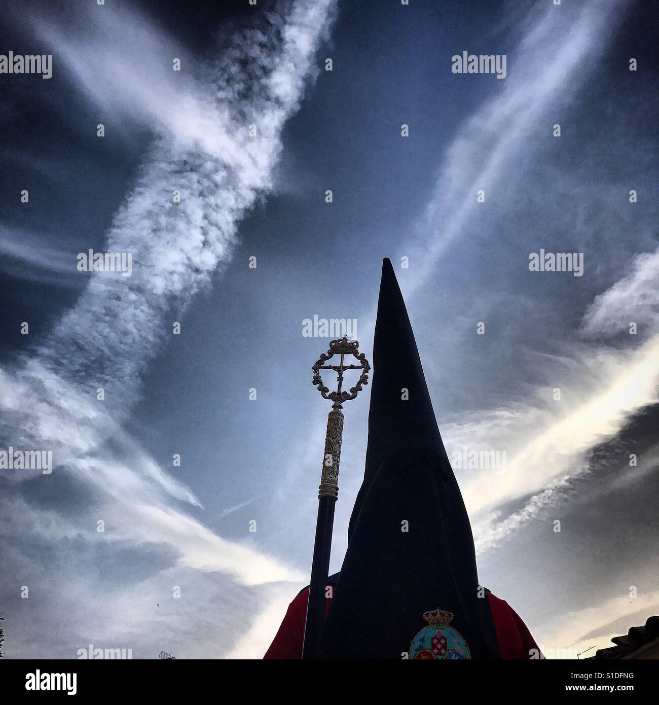 Ein Spitzen Kapuzen Büßer unter freiem Himmel bedeckt mit Chemtrails, während der Osterwoche in Baeza, Provinz Jaen, Andalusien, Spanien Stockfoto