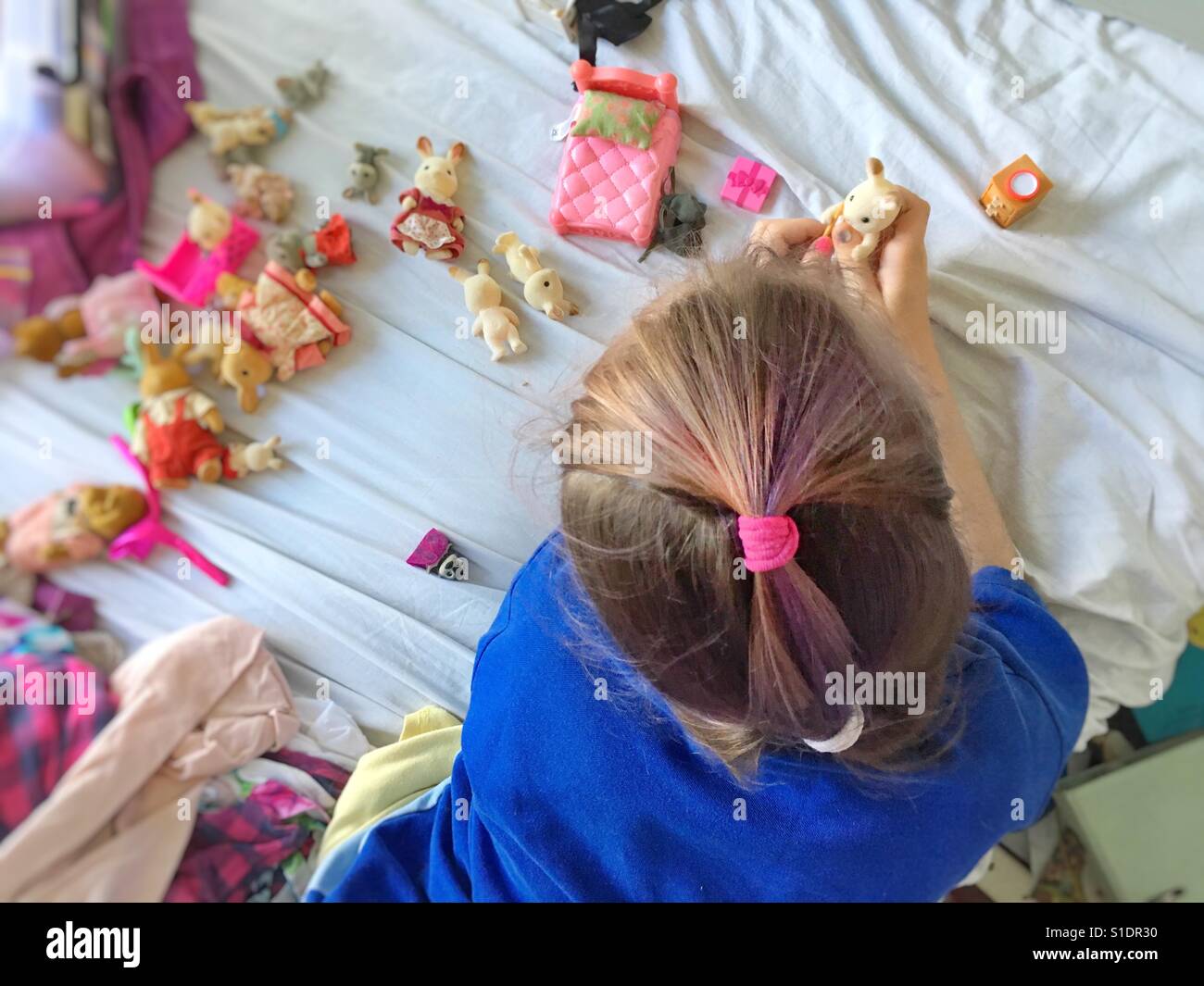 Schen Mädchen spielen mit Spielzeug auf einem Bett. Stockfoto