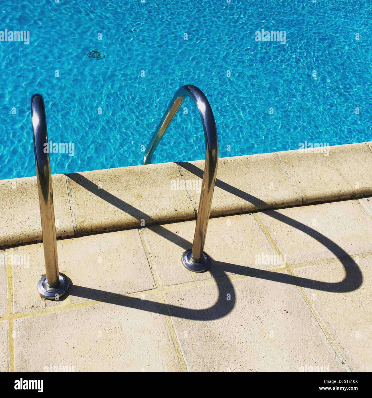 Grafische, halb abstrakte Form der Schatten der Außenschwimmbadleiter. Mobiltelefon-Foto mit einem Telefon oder Tablet Nachverarbeitung. - Smartphone-aufgenommenes Stockfoto