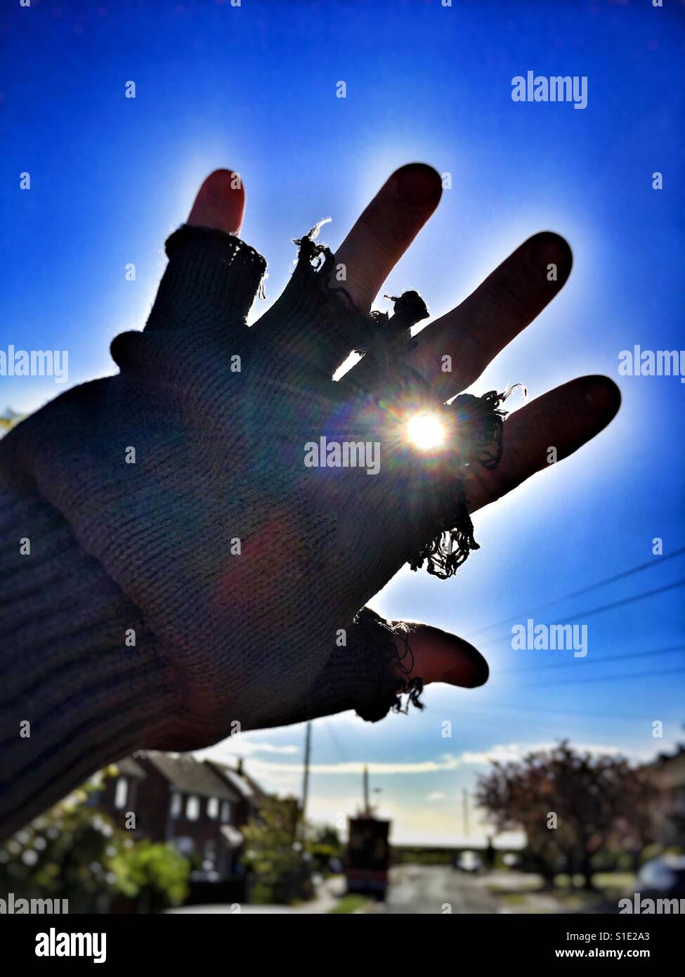 Behandschuhte Hand blockiert die Sonne Stockfoto