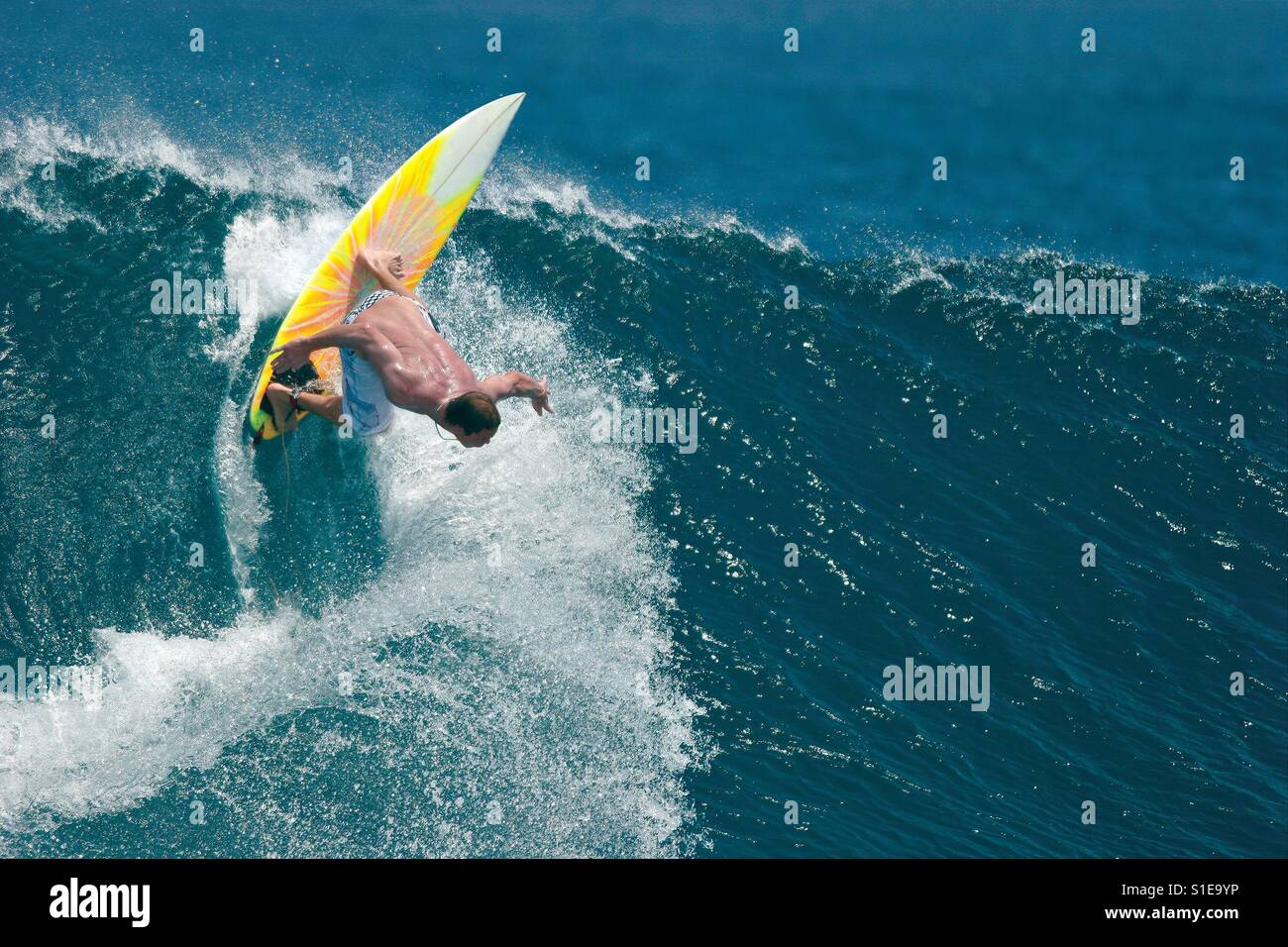 Eine männliche Surfer führt einen radikalen Schritt auf eine schöne blaue Meereswelle. Stockfoto