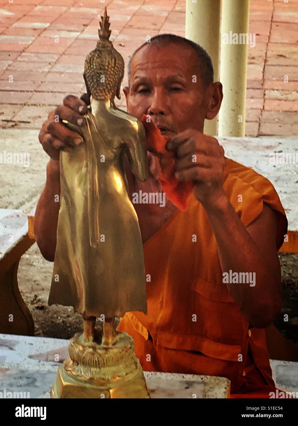 Theravada-buddhistischen Mönch poliert eine Buddha-Statue Stockfoto