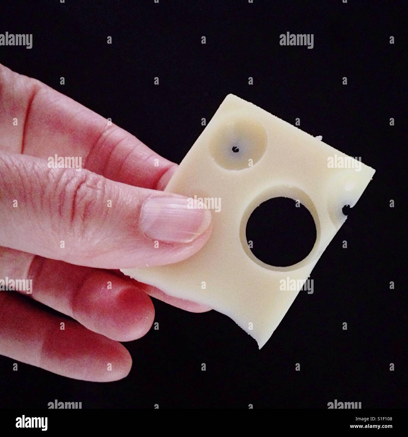 Hand hält eine Scheibe Emmentaler Käse - Smartphone-aufgenommenes Stockfoto