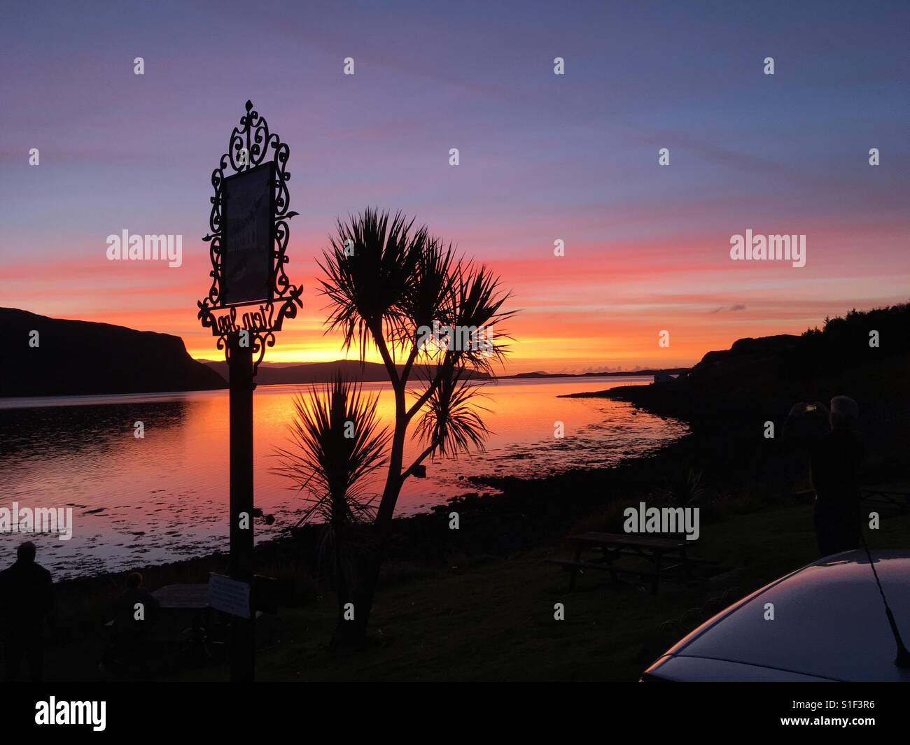 Sonnenuntergang aus Stein auf der Insel Skye von Loch Bay Blick auf The Minch mit Eaval / Eabhal 347 Meter auf North Uist in den äußeren Hebriden Western Isles - OotThere Stockfoto