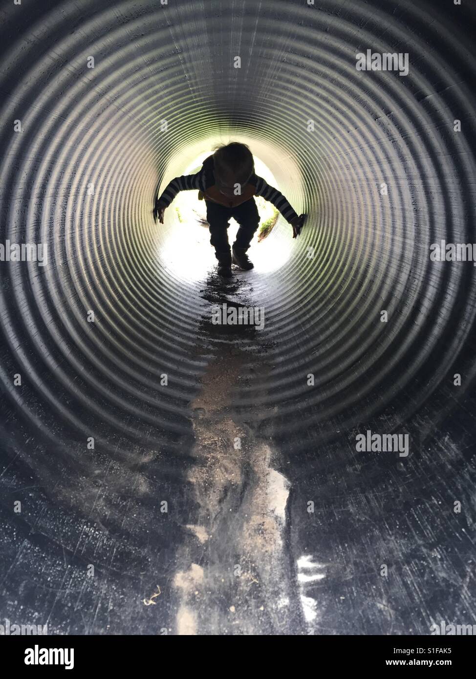 Kleiner Junge spielt in einem Tunnel in ein Abenteuer-Spielplatz Stockfoto