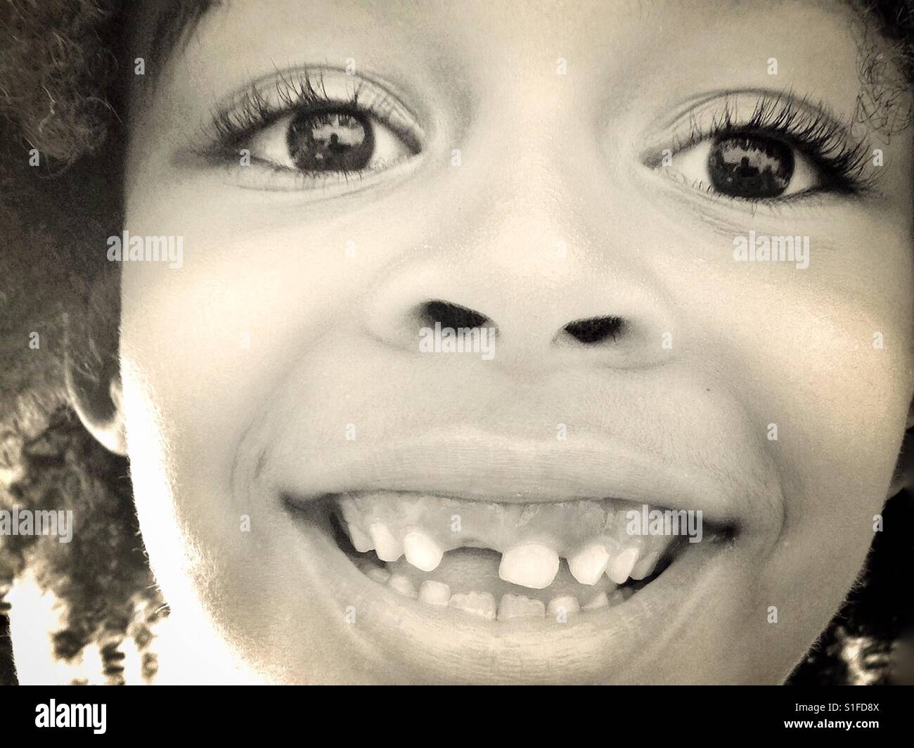 Ein junges Mädchen Lächeln auf den Lippen und zeigt ihre fehlenden Zahn. Stockfoto