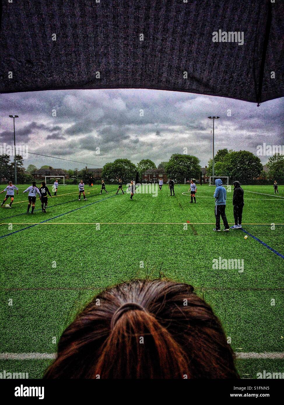 Fußball gucken Mädchen im Regen Stockfoto