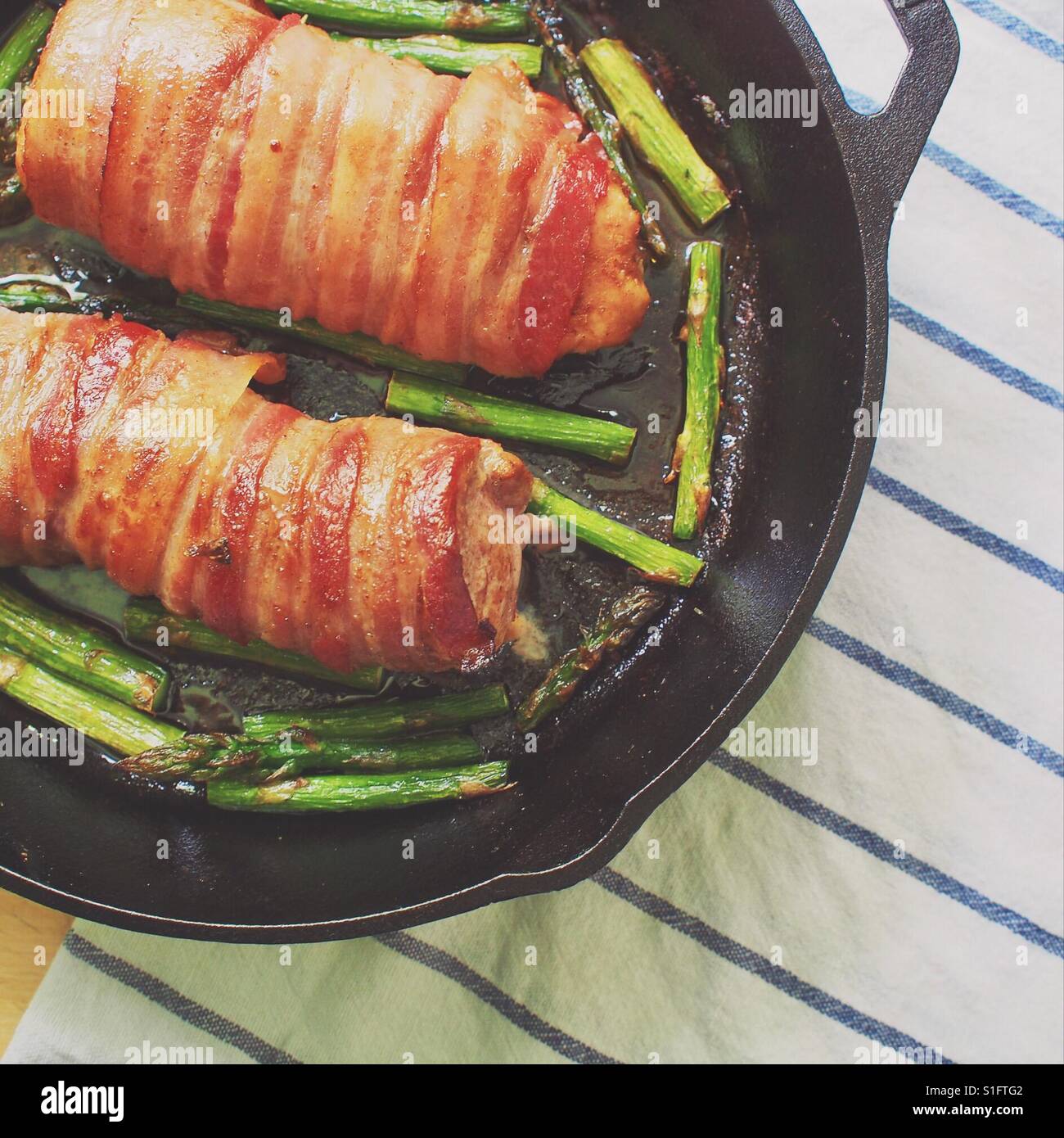 Speckmantel Schweinefilet in einer gusseisernen Pfanne mit Spargel Stockfoto