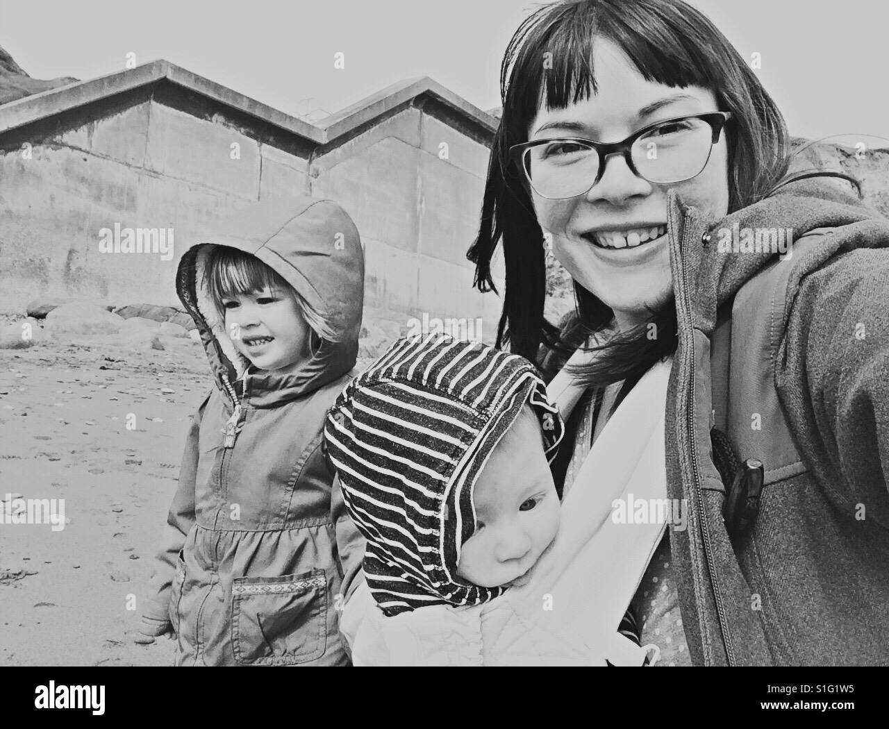 Mutter und Kinder am Strand Baby tragen Kleinkind Stockfoto