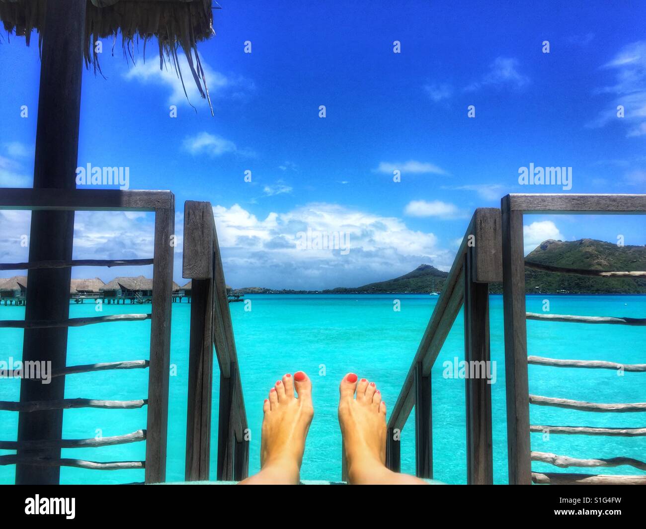 Füße mit lackierten Zehennägeln auf dem Deck eine Overwater Bungalow in Bora Bora, Südsee Stockfoto