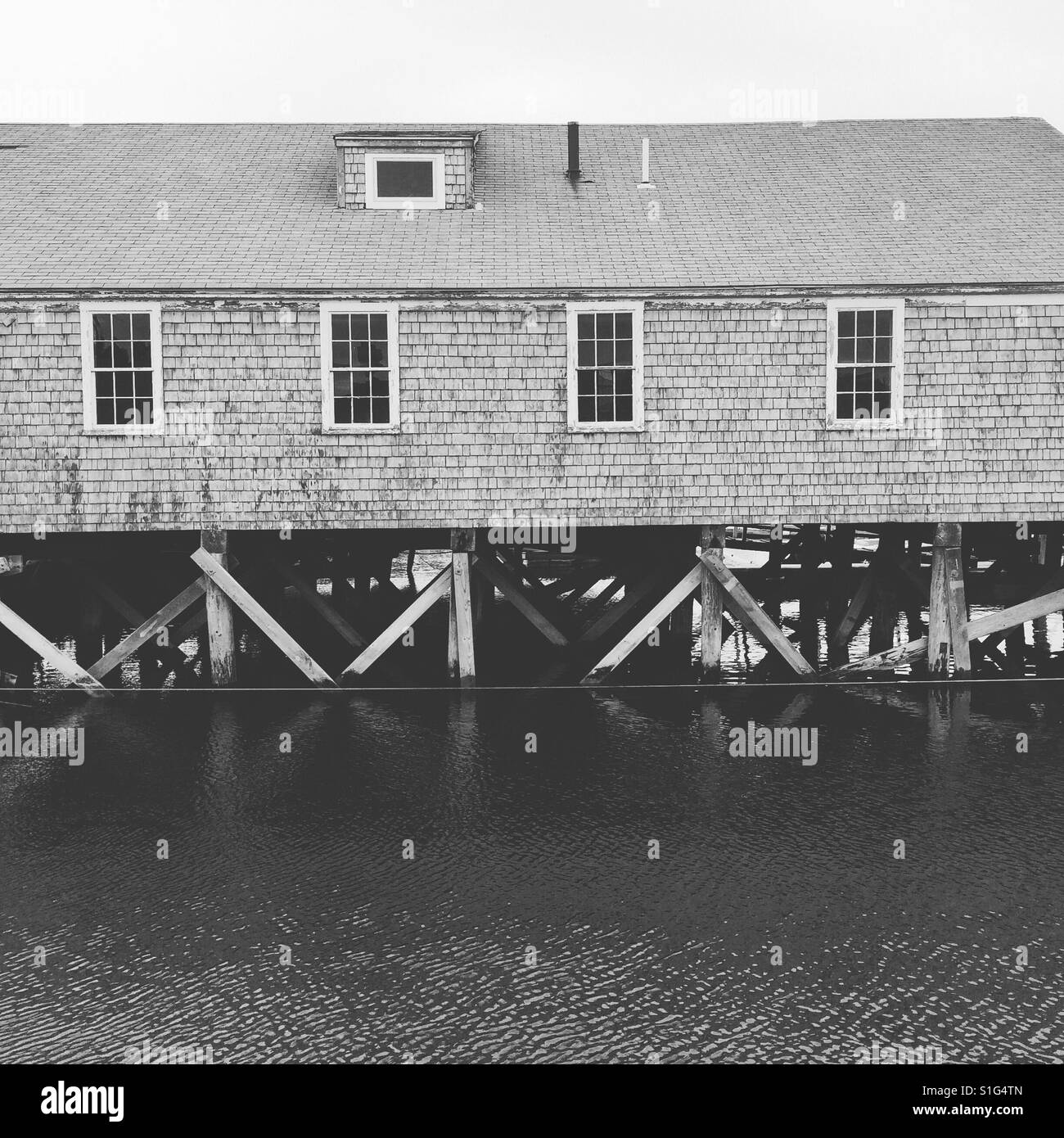 Ein altes Gebäude auf dem Wasser in Barnstable Harbor, Cape Cod - Smartphone-aufgenommenes Stockfoto