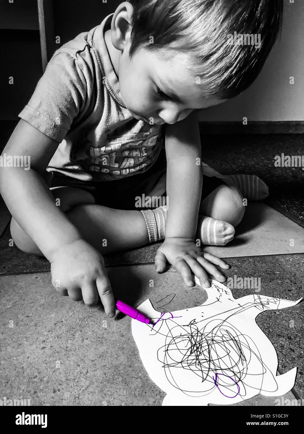 Kleiner Junge auf einem kleinen Stück Papier zeichnen Stockfoto