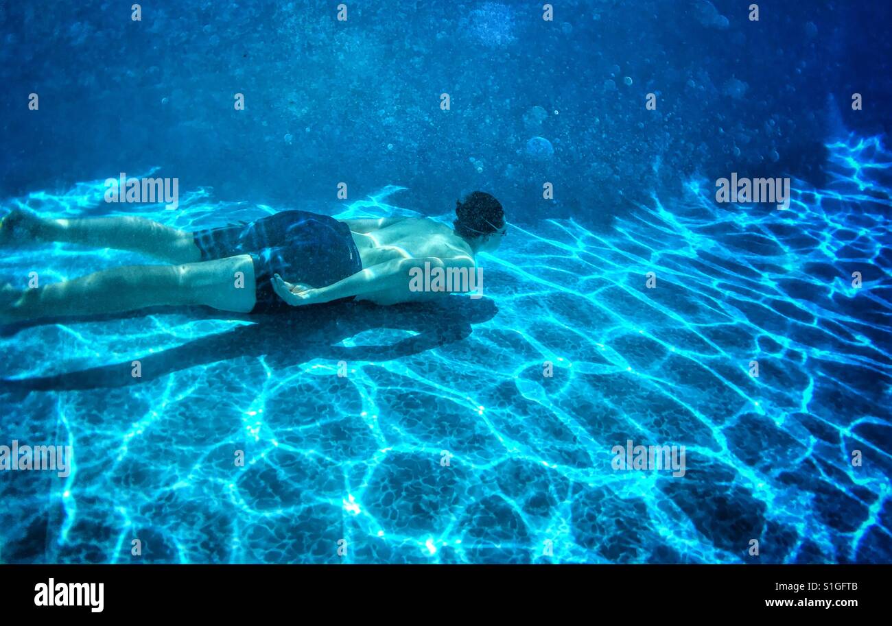 Teenager unter Wasser schwimmen im Außenpool. Stockfoto