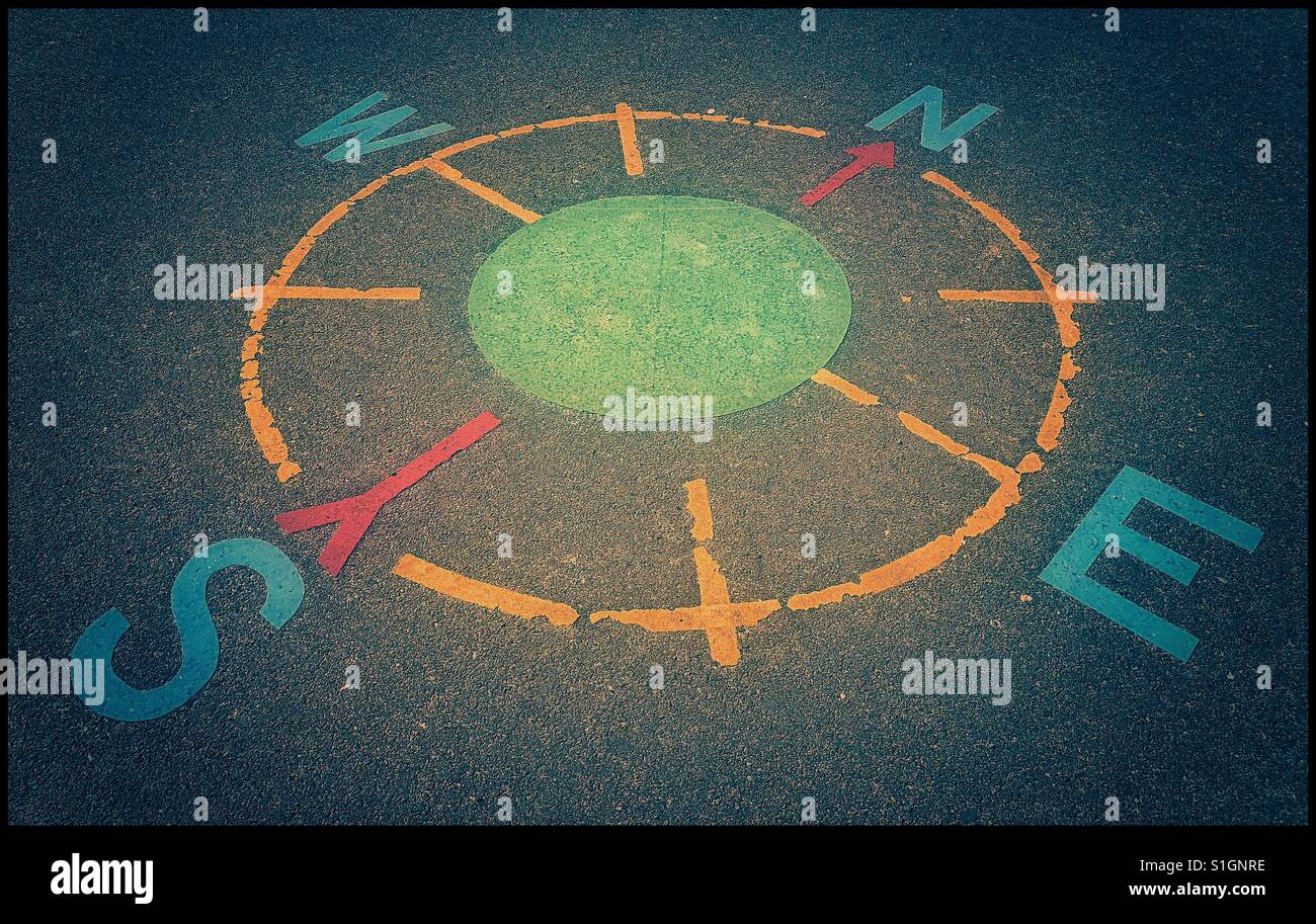Ein bunte Kompass geätzt auf den Boden eines Kindes Spielplatz. Der rote Pfeil ist Norden. Die 4 Himmelsrichtungen sind der Ursprung des Wortes 'News' Photo Credit - © COLIN HOSKINS. Stockfoto