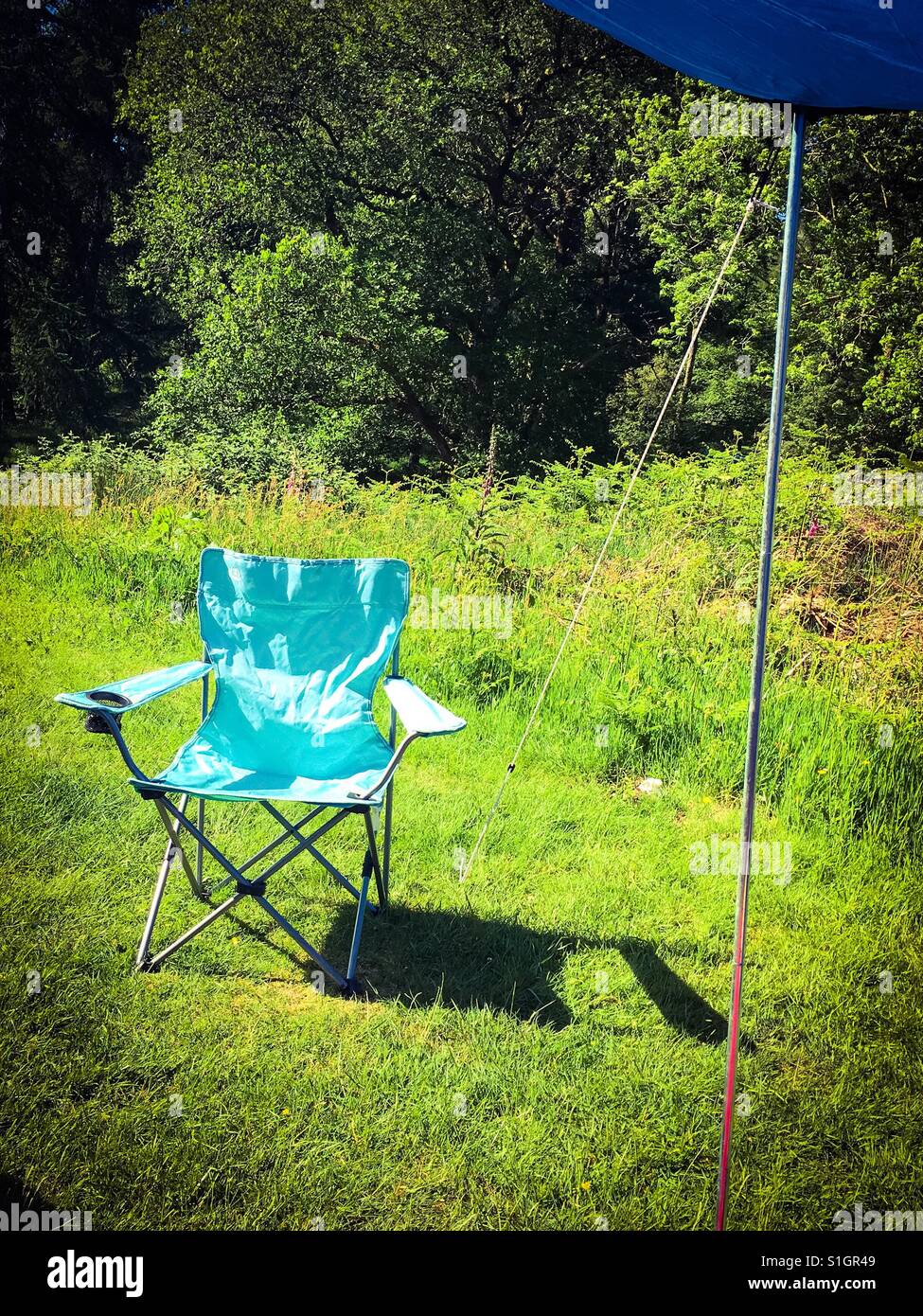 Ein leichtes Blau Campingstuhl eingerichtet, neben einem Zelt in der Sonne. Stockfoto
