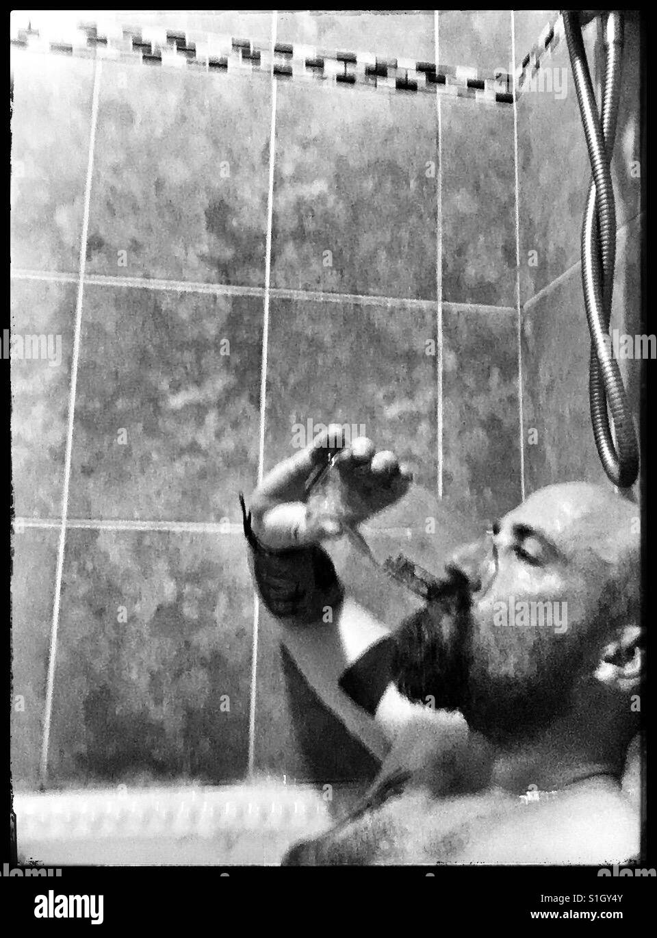 Man trinkt ein Bier in der Badewanne. Stockfoto