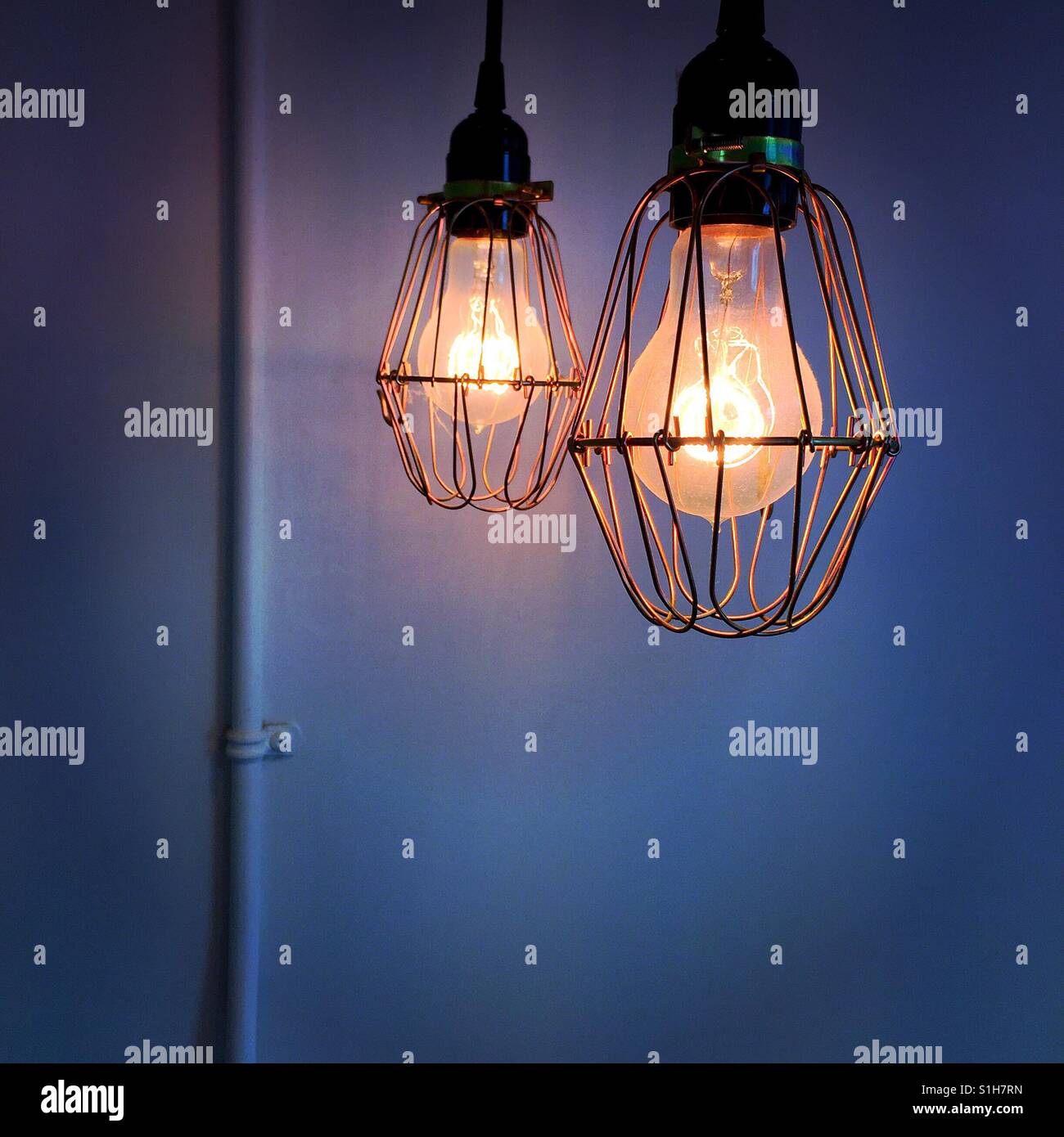 Hängen zwei Wolfram Lichter vor einer leeren Wand mit nur eine elektrische Leitung drauf Stockfoto