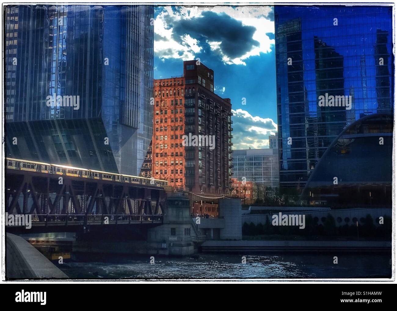 Sonne durch die Wolken spähen erhöht gerade genug, um aus dem Metall der Chicago reflektieren 'el' Zug Reisen über den Chicago River. Stockfoto