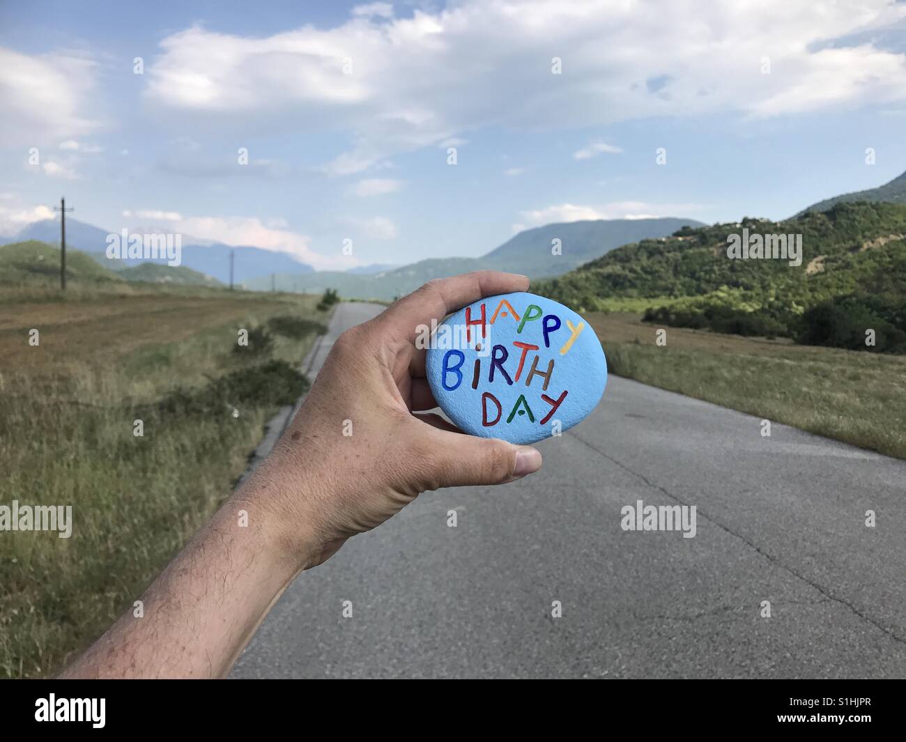 Happy Birthday Stein mit Gebirgshintergrund Straße Stockfoto