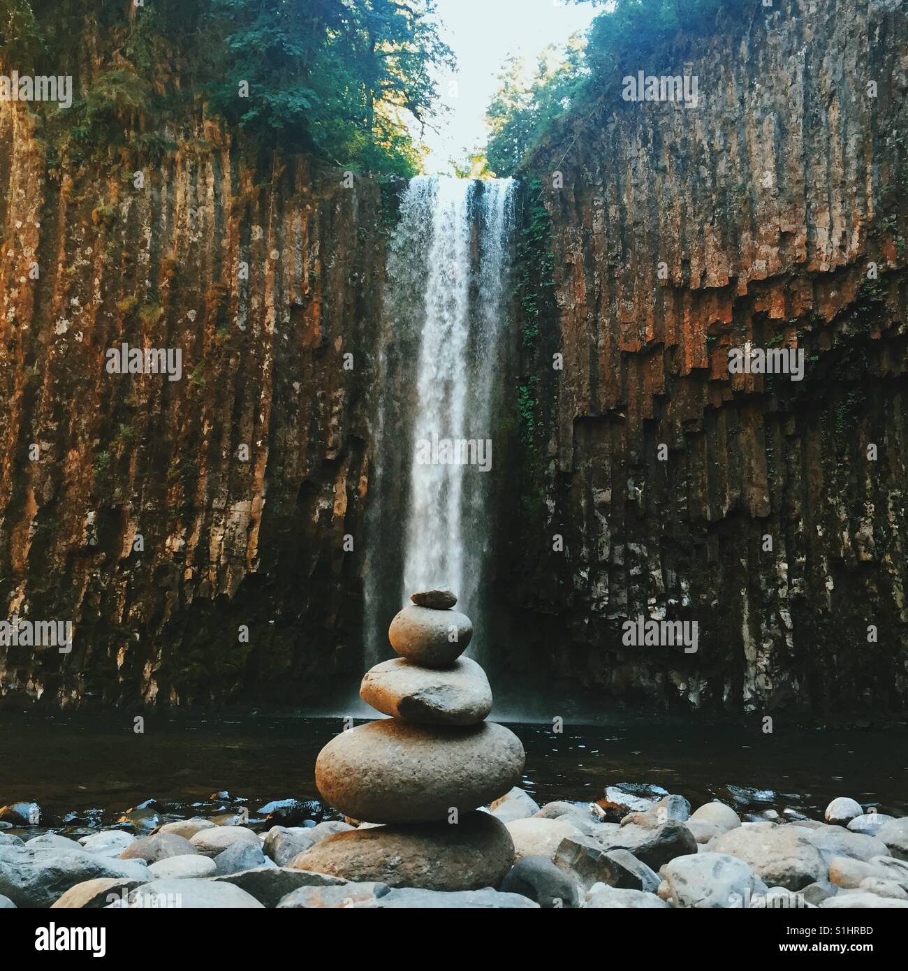 Ein Steinhaufen links am Fuße eines Wasserfalls in Oregon. Stockfoto