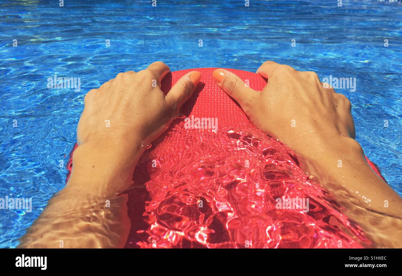 Nahaufnahme von Frauenhand festhalten an einem Kick Board beim Schwimmen im Außenpool. - Smartphone-aufgenommenes Stockfoto