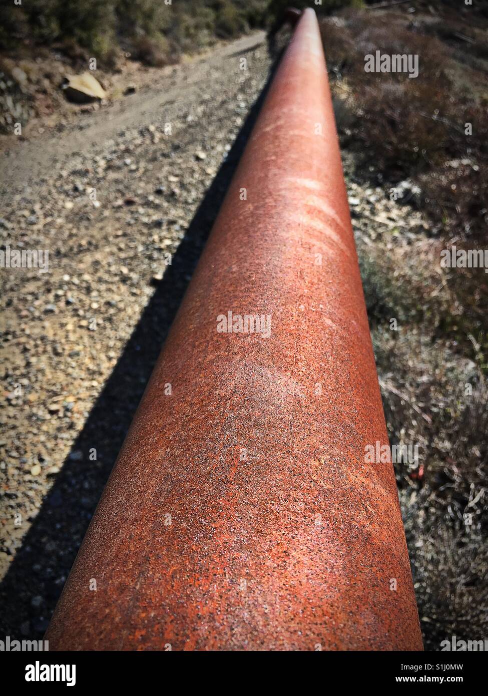 Eine rostige alte Rohr in der Nähe von einem Feldweg erweitert in den Horizont Stockfoto