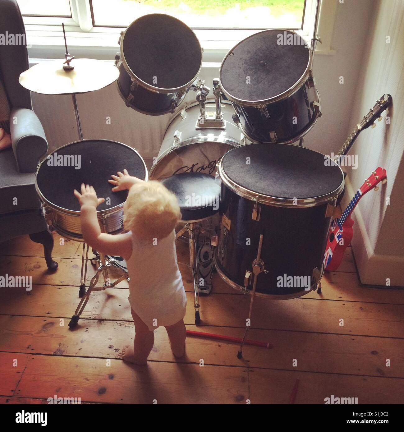 Zehn Monate altes Baby junge Schlagzeug spielen - Smartphone-aufgenommenes Stockfoto