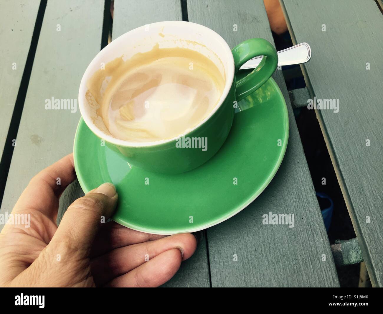 Kaffee in einer grünen Schale auf einem hölzernen Hintergrund - Smartphone-aufgenommenes Stockfoto
