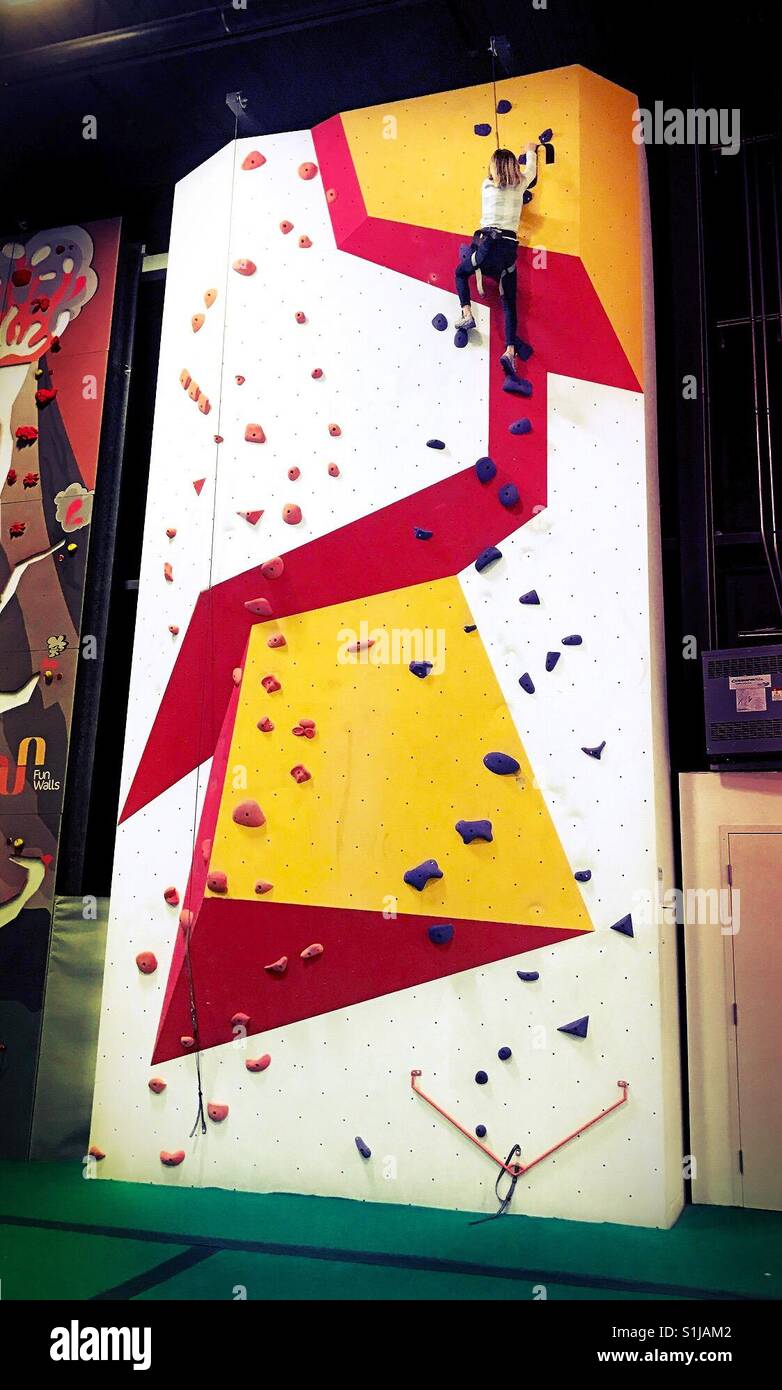 Eine Mädchen erreicht den oberen Rand eine indoor-Kletterwand. - Smartphone-aufgenommenes Stockfoto