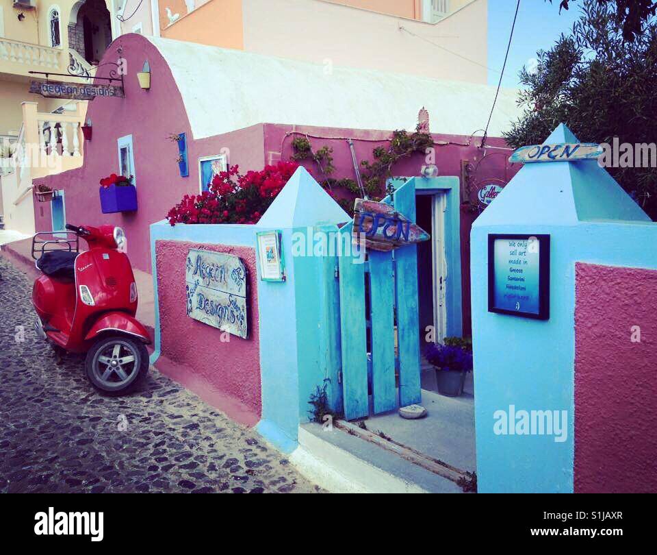 Griechische Straße gefärbt in rot mit niedlichen roten Vespa vorne geparkt Stockfoto