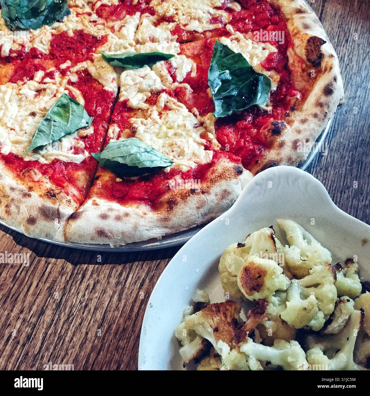 Vegane Pizza auf Metallplatte Snd Schüssel mit geröstetem Blumenkohl Stockfoto