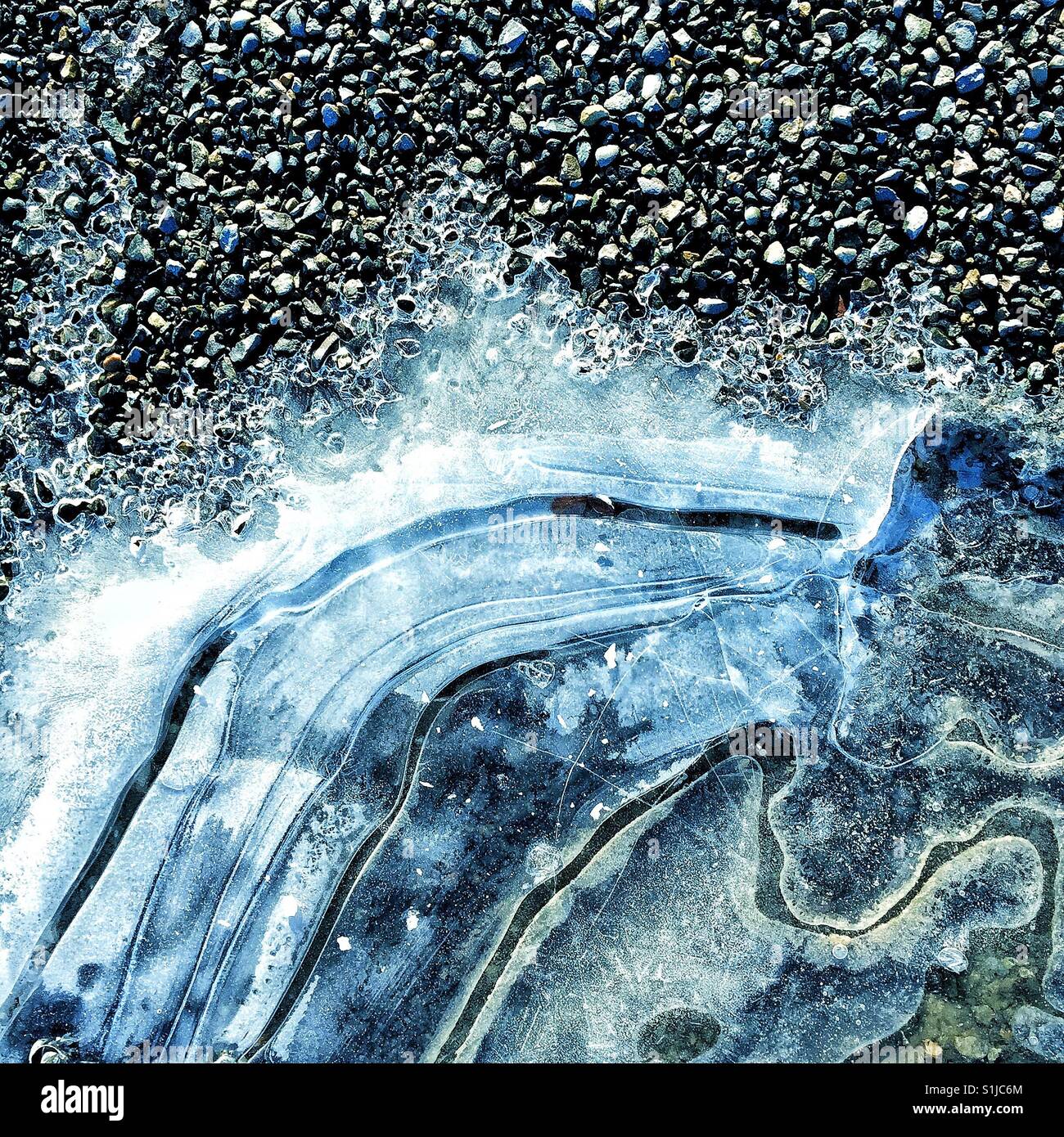 gefrorenes Wasser auf dem Kies Stockfoto