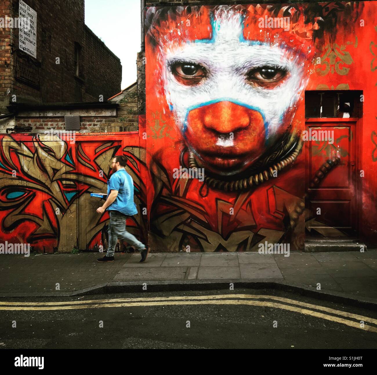 East London Street Art und Mann - Smartphone-aufgenommenes Stockfoto