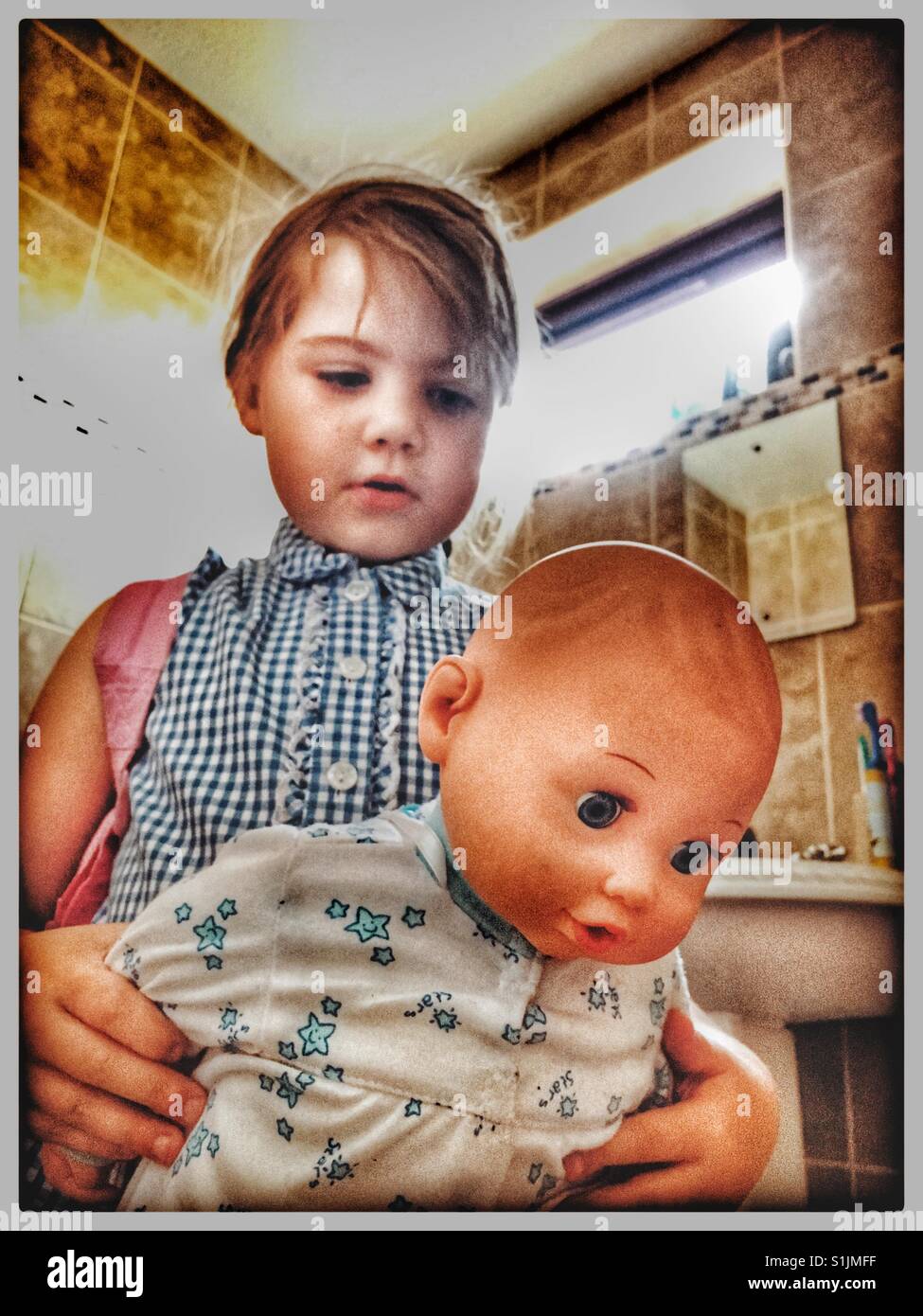 Junges Mädchen rund um ihre Puppe in der Badewanne dunk. Stockfoto