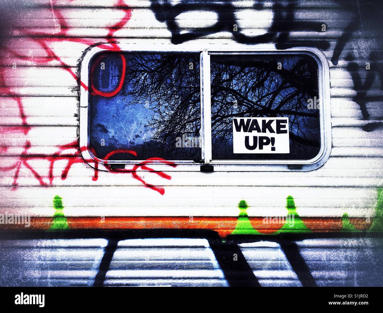 Fenster von einem Graffiti bedeckt Wohnmobil mit Schild Wake Up Stockfoto